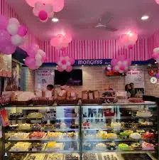 Monginis cake shop with a cake display and pink balloon decorations