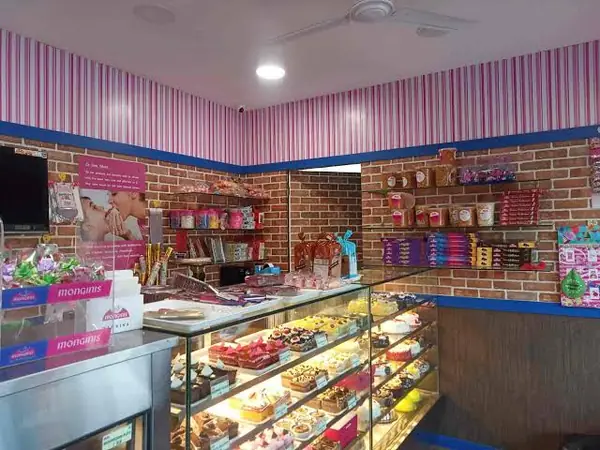 Pink-striped Monginis shop with gift shelves and a display chiller